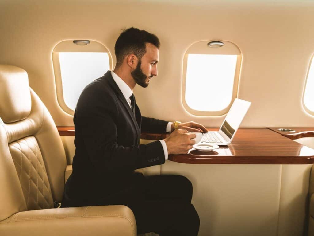 Businessman working on a laptop inside a private jet cabin.